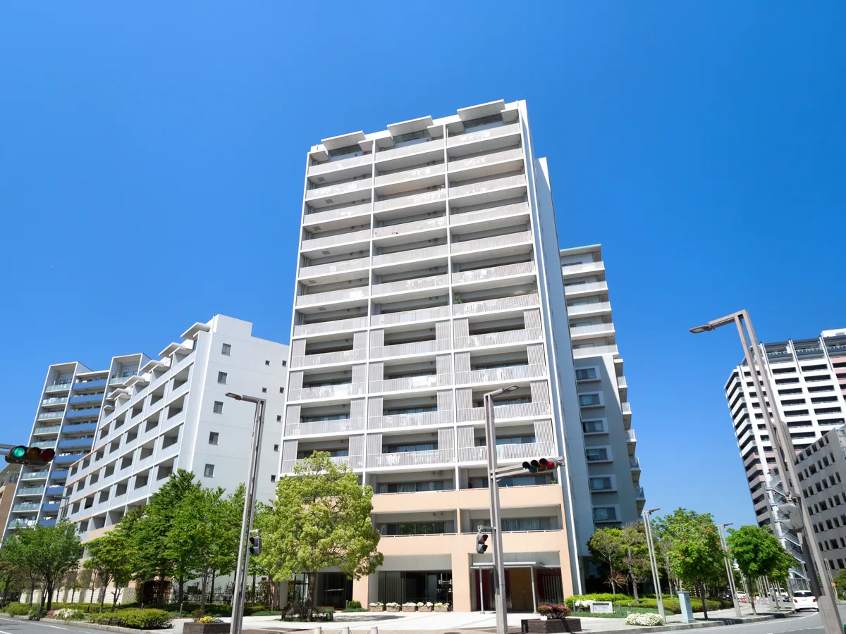 青空にそびえる白い高層マンション