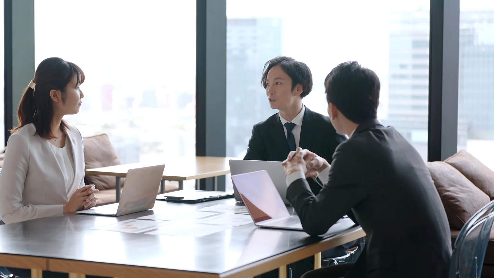 窓際のテーブルで向き合う商談