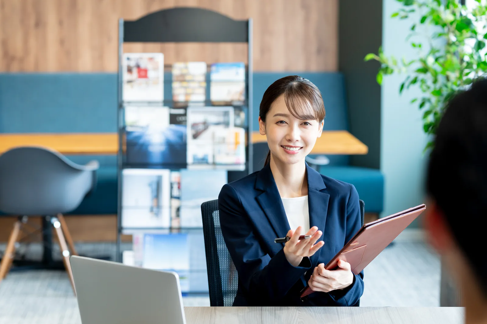 受付に立つ紺のスーツの女性