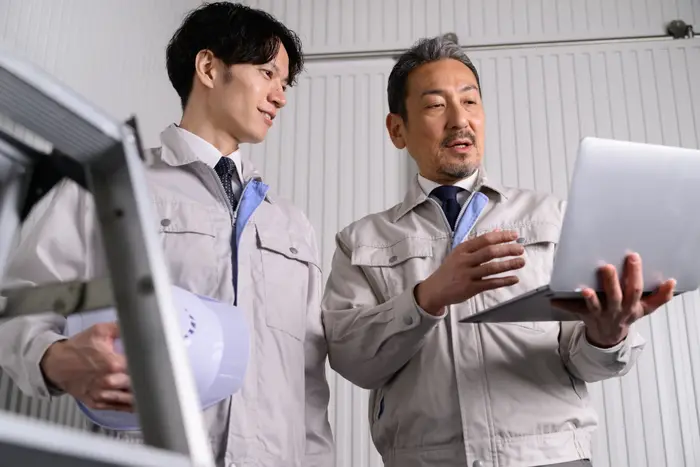 ノートパソコンを前に打ち合わせる社員2名